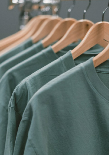 The tops of green t-shirts on hangings